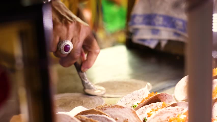 Vendor prepares Thai crispy pancakes on hot griddle, vibrant street food market, natural lighting