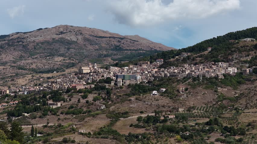Aerial drone view of Petralia Sottana, a historic Sicilian mountain town surrounded by scenic hills and the Madonie Mountains, featuring traditional stone houses and panoramic landscapes, Sicily Italy
