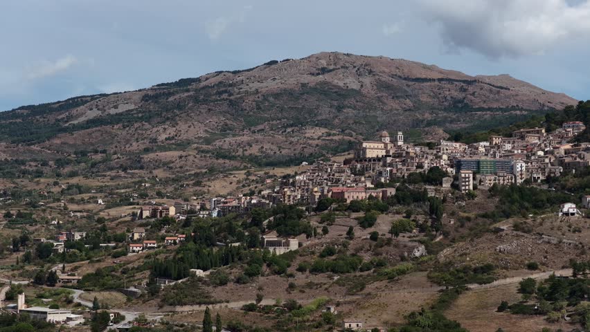 Aerial drone view of Petralia Sottana, a historic Sicilian mountain town surrounded by scenic hills and the Madonie Mountains, featuring traditional stone houses and panoramic landscapes, Sicily Italy