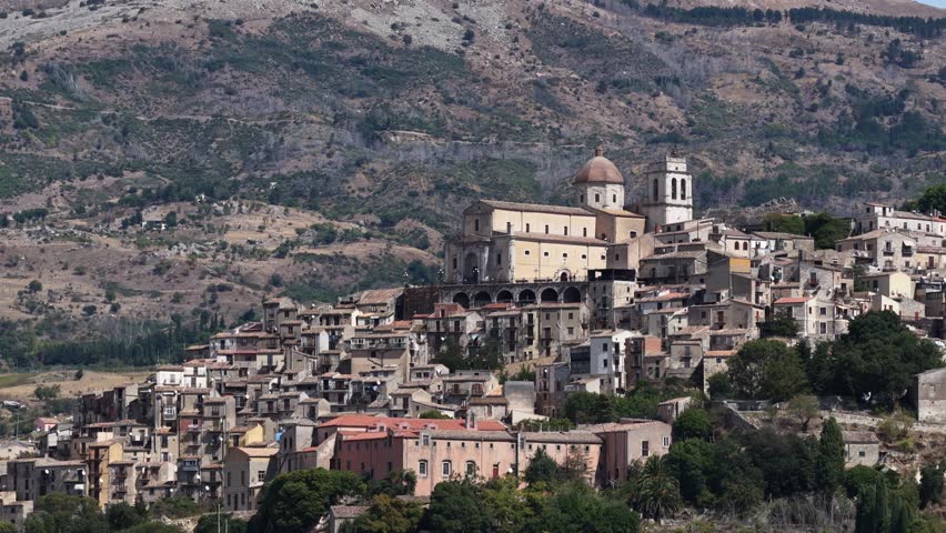 Aerial drone view of Petralia Sottana, a historic Sicilian mountain town surrounded by scenic hills and the Madonie Mountains, featuring traditional stone houses and panoramic landscapes, Sicily Italy