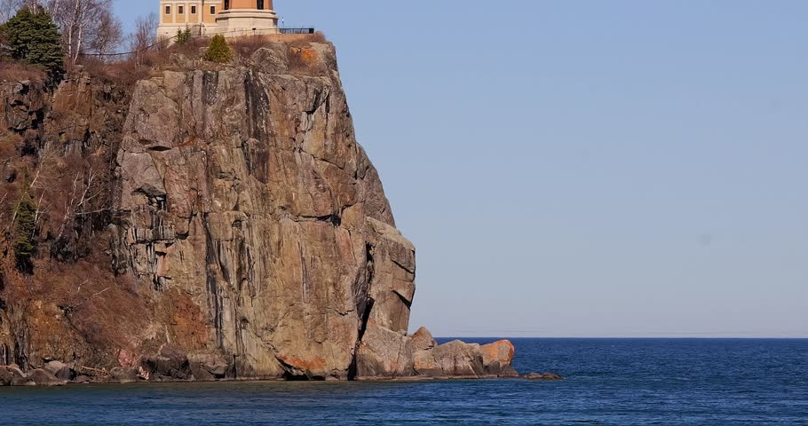 Dramatic rock cliff holds the popular landmark, Split Rock Lighthouse, above the blue water at the North Shore of Lake Superior in northern Minnesota on a sunny spring day.