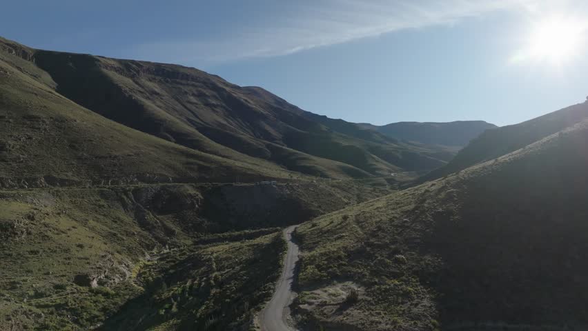 Aerial view of mountain valley with green slopes and sunlight creating shadows