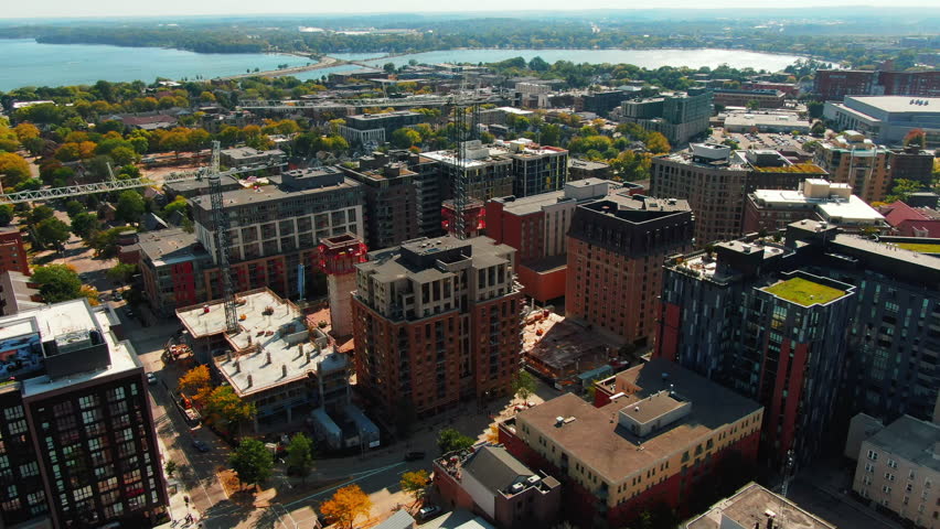 Aerial Circling Shot of an Urban Construction Site Overlooking a Waterfront Cityscape in Autumn