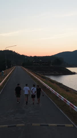 Tourists Walking on a dam road at sunset near the lake