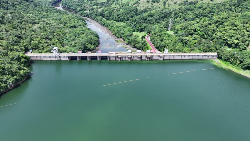 4k aerial video footage flying across Bayano Lake in Panama, toward Bayano Dam with Hydroelectric Power Plant, with right panning above the Dam, with rainforest and jungle landscape around the lake