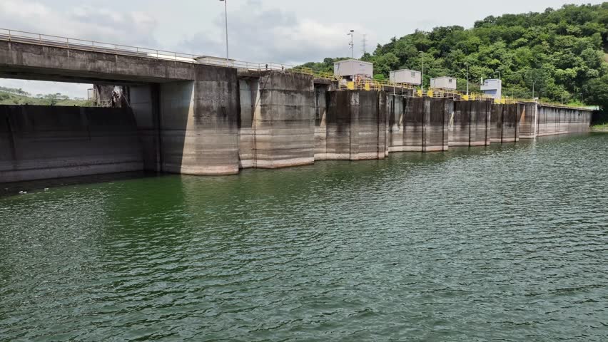Flying low level along and away Bayano Dam with Hydroelectric Power Plant, located at Bayano Lake - Panama rainforest landscape in background - 4k aerial video footage