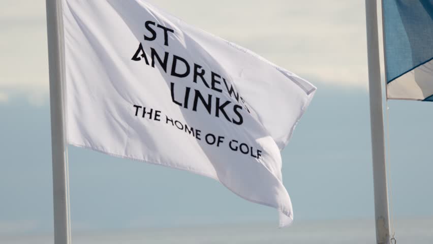 White St Andrews Links flag waves briskly in daylight wind, steady camera, soft natural lighting