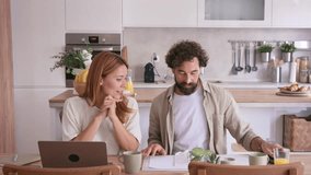 Young couple sitting at the kitchen table checking bills and receipts, managing their household budget and expenses together while using a laptop for online banking and financial planning - Powered by Shutterstock - Get 15% off with code: PIKWIZARD15