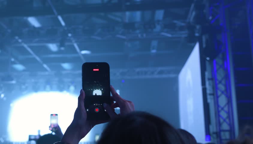 fan shooting music concert performance with mobile phone. Blue neon lights. 8K footage. Fan crowd shoot DJ live concert.