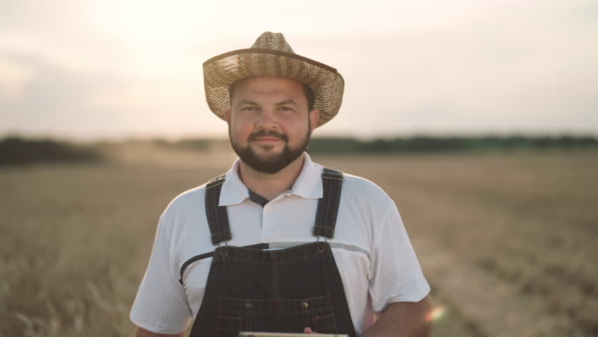 Agribusiness and agriculture, portrait of happy farmer with tablet in fields. Growing cereals for food industry, walk in beautiful rye and wheat farmland in summer day, traditions and innovation