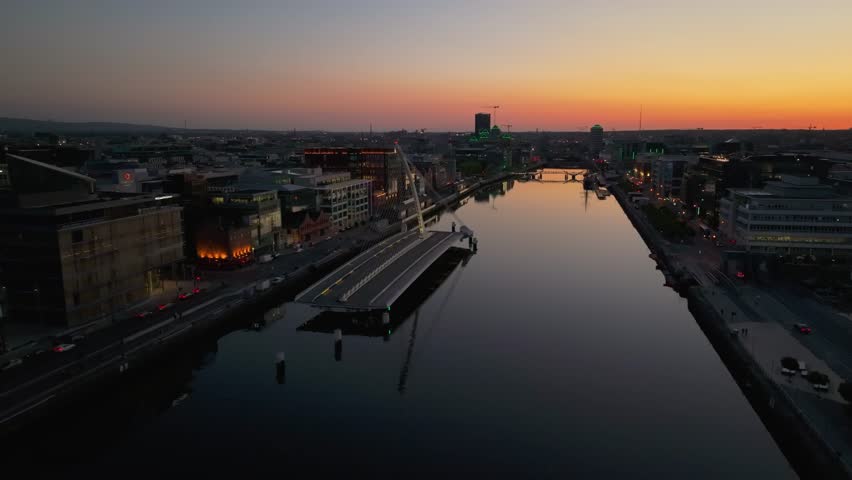 4K cinematic drone footage capturing a golden sunset over Dublin’s Samuel Beckett Bridge during a rare moment when it’s open, with stunning reflections on the River Liffey. Co. Dublin, Ireland_220