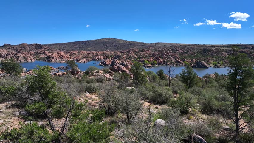 Aerial view of Watson Lake showing a person standing on rocks with the lake surrounded by rugged terrain and sparse vegetation, Watson Lake, Arizona, United States.