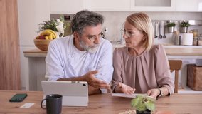 Worried senior couple having a heated argument while discussing domestic bills and finances, feeling stressed about debt and expenses while sitting together at their kitchen table at home - Powered by Shutterstock - Get 15% off with code: PIKWIZARD15