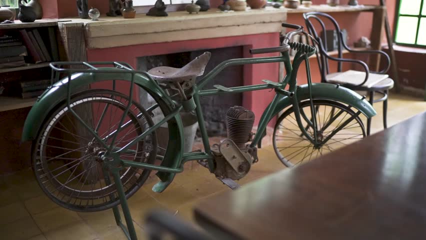 A vintage green motorized bicycle an early motorcycle displayed as an antique exhibit inside a historic house museum in Misiones Argentina