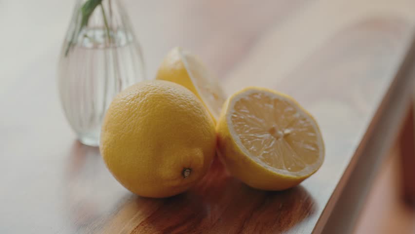 Close up of fresh lemons on wooden table beside small glass vase