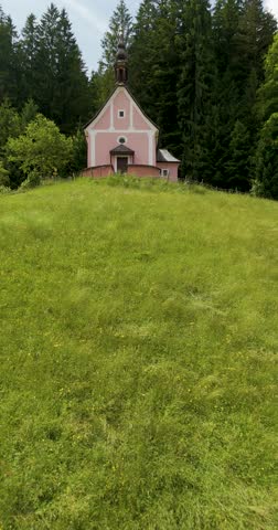 "Kalvarienbergkirche" at "Gosau" Austria old pink church on a hill with mountains in the back