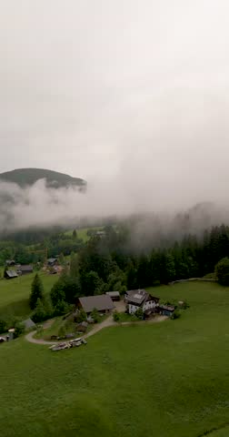 small village "Gosau" in Austria overflowed with fog and clouds. Drone aerial with mountains in the back
