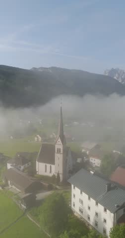 "Pfarrkirche" "Gosau" in Austria old gothic church peaking through the clouds in a valley
