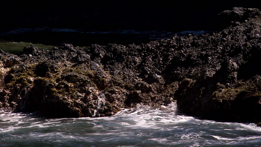 Still shot of waves crashing on rocks