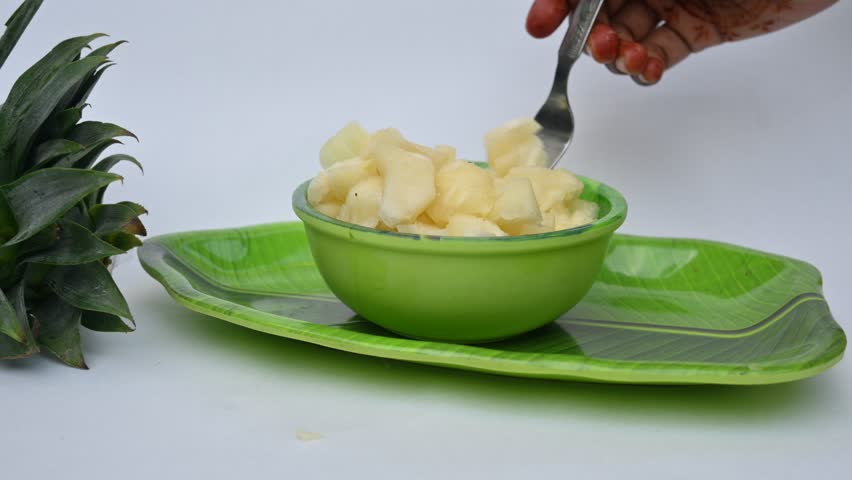 Pineapple or Ananas comosus slices on white background. It is a tropical plant with an edible fruit. It is plant in the family Bromeliaceae. Pineapple pieces in a bowl ready to eat.