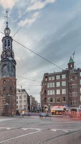 Munttoren tower and flowers market. Panoramic timelapse hyperlapse of Amsterdam city center featuring street traffic with trams under colorful cloudy sky. Scenic urban view during sunset. Netherlands