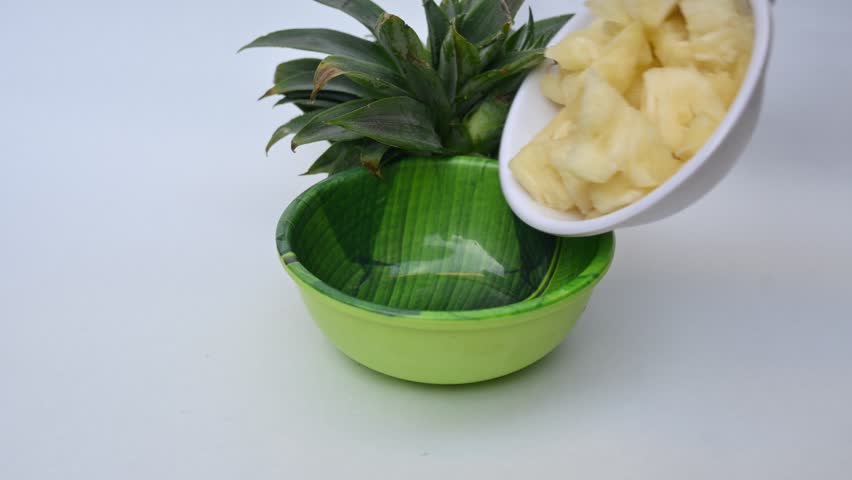 Pineapple or Ananas comosus slices on white background. It is a tropical plant with an edible fruit. It is plant in the family Bromeliaceae. Pineapple pieces in a bowl ready to eat.