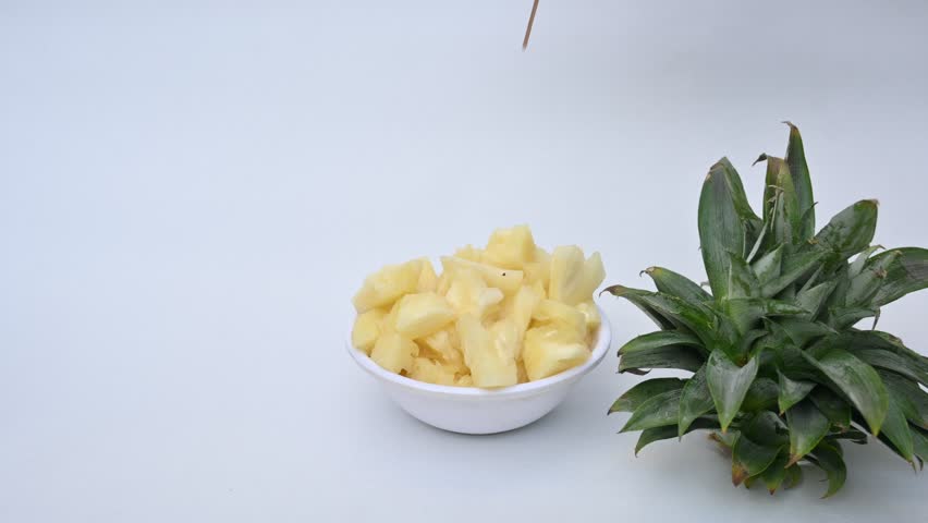 Pineapple or Ananas comosus slices on white background. It is a tropical plant with an edible fruit. It is plant in the family Bromeliaceae. Pineapple pieces in a bowl ready to eat.