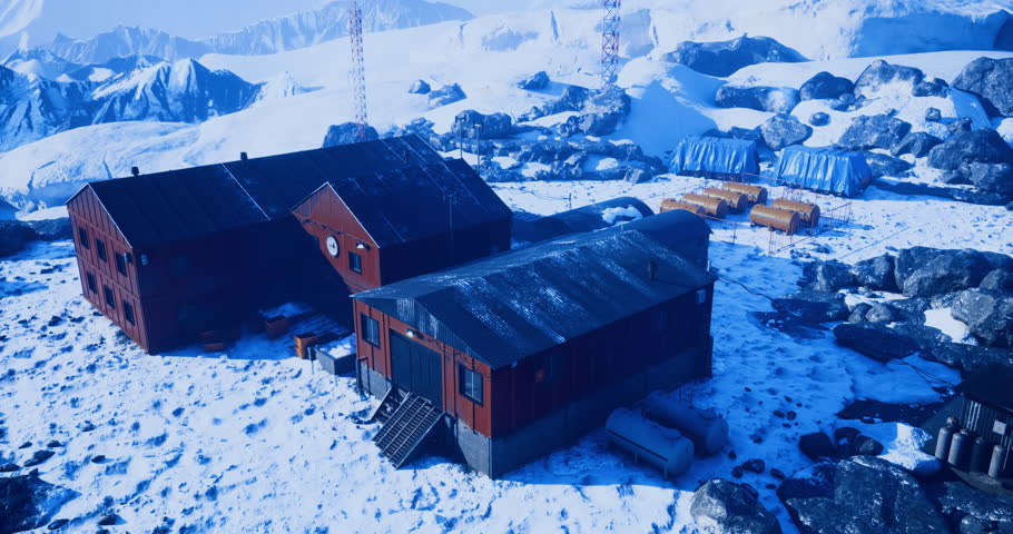 Red structures stand amidst snow and ice, surrounded by towering mountains. Communication towers rise, indicating a remote research site in a harsh winter environment.