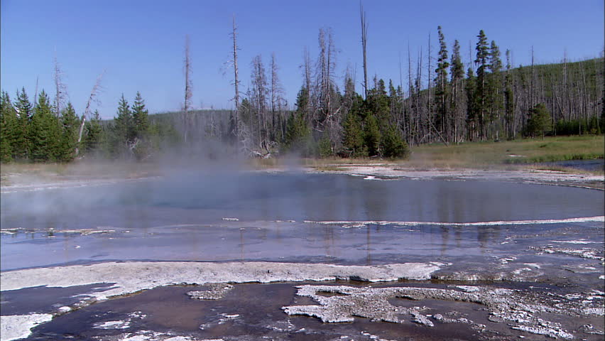 Still shot of a smoking body of water from a geyser