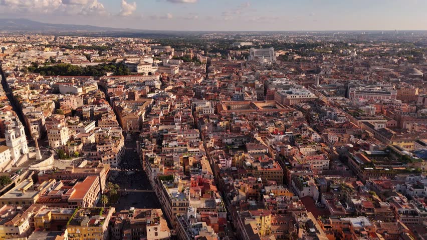 Aerial drone panoramic view of Rome with iconic rooftops, terracotta tiles, domes, and historic architecture under sunny sky, capturing timeless Italian cityscape charm