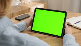 Woman sit desk use click digital tech tablet, green screen mock up. Hand swipe ipad web site. Girl hold pad closeup press tap touch middle. Chroma key page. Cozy home background. Online app copy space - Powered by Shutterstock - Get 15% off with code: PIKWIZARD15