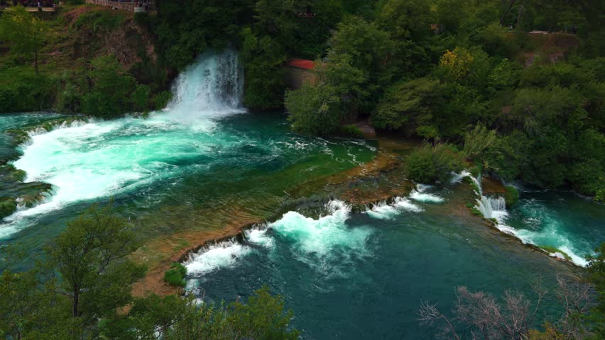 Crystal clear cascades surrounded by lush forest and historic mill in Krka National Park, Croatia