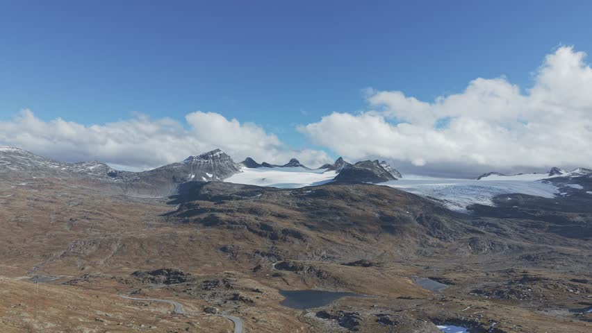 Areal footage of clouds running over mountain peaks and glaciers in Jotunheimen National Park, Norway