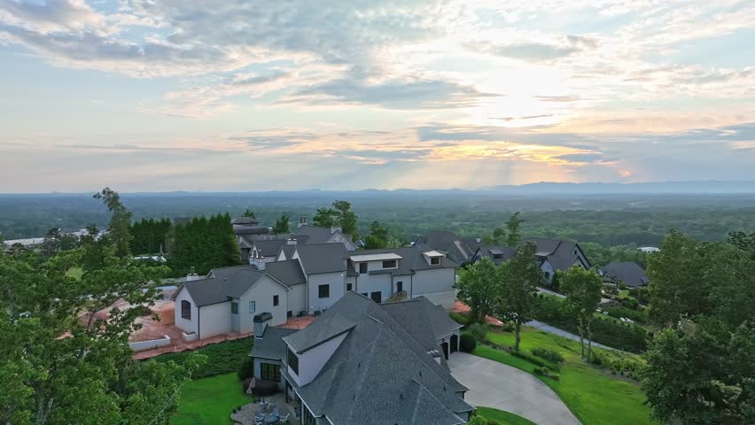 Large houses sit atop a hill in the Montebello Subdivision of Greenville, SC with a mountain range in the background.