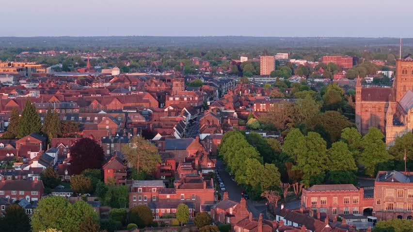 A cinematic parallax drone shot sweeps over St Albans city, gradually revealing the majestic cathedral rising above the urban landscape.