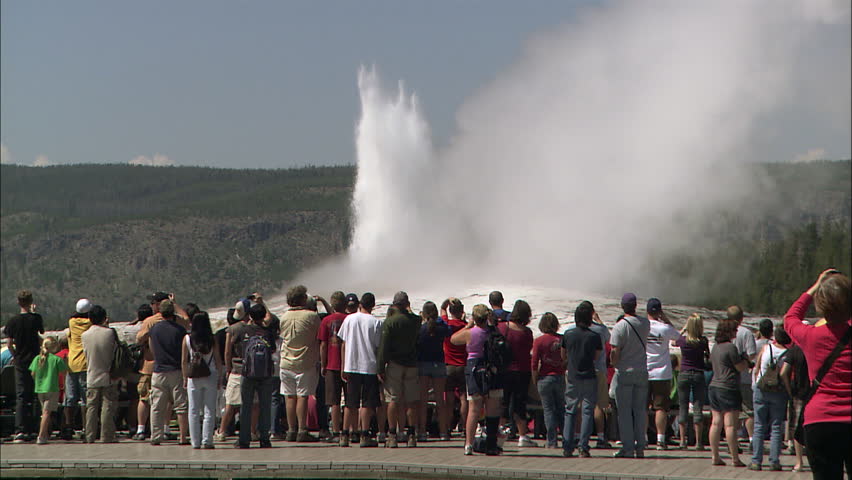 Shot of old faithful erupting with people in line