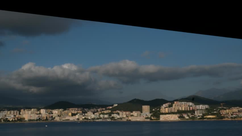 Scenic coastline of Corsica island seen from cruise ship with green hills rocky cliffs turquoise sea and coastal towns in sunlight Mediterranean travel destination natural landscape and summer view