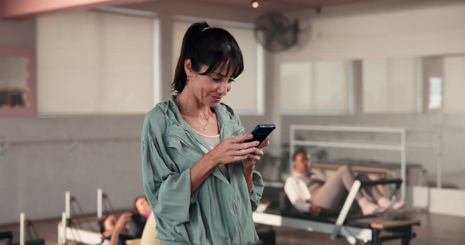 Happy, pilates and woman in studio, cellphone and funny meme with wellness, exercise and internet. Mature person, humor and instructor with smartphone, connection or social media with fitness or app