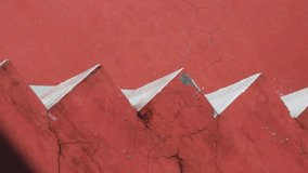 Abstract closeup of a textured red wall with a repeating pattern of sharp, angular, lightcolored geometric shapes creating a zigzag effect 4k video footage - Powered by Shutterstock - Get 15% off with code: PIKWIZARD15