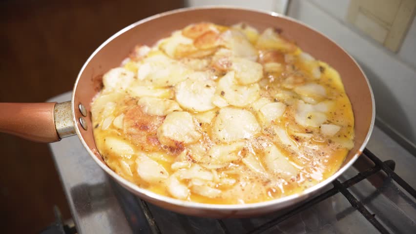 Cooking in a pan a traditional homemade Spanish omelette 