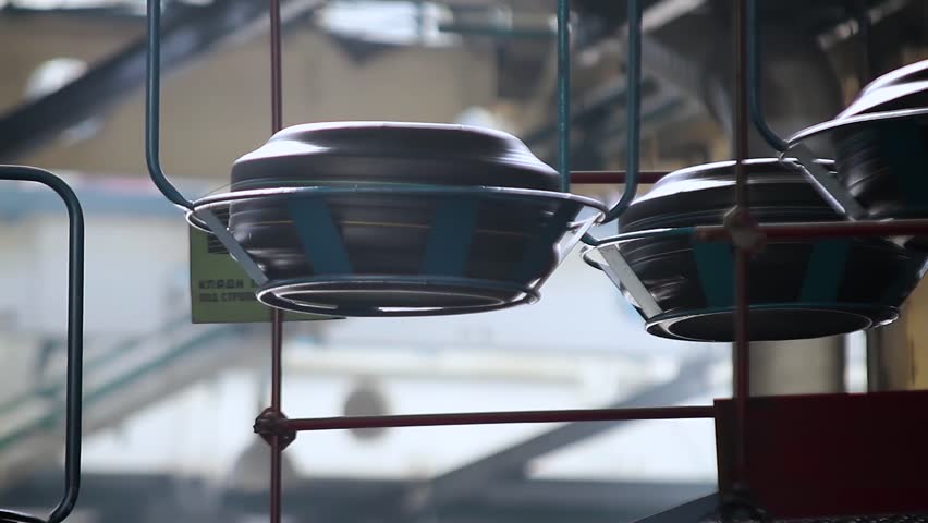 Manufacture of automobile tyres. Moving conveyor transfers formed rubber tires along large manufacturing plant workshop.