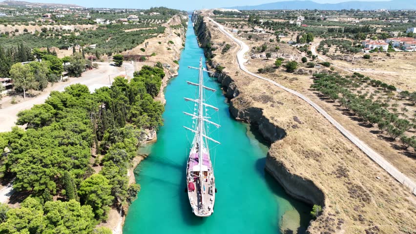 Aerial drone cinematic video of classic sailing boat crossing narrow Corinth canal of Isthmus from West submersible bridge and narrow opening of Corinthian gulf to Saronic gulf, Loutraki, Greece