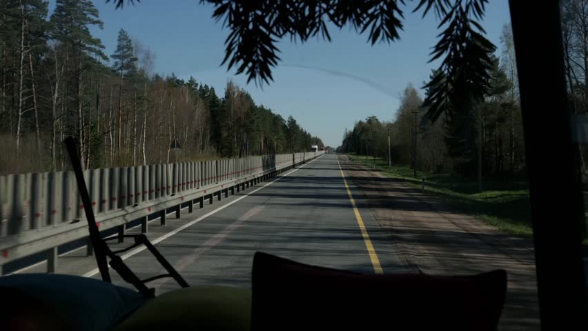 View of a straight road surrounded by trees. The scene captures a clear sky and a peaceful atmosphere, ideal for travel and adventure themes.