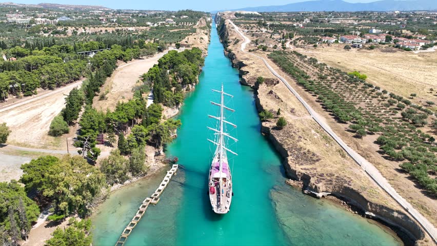 Aerial drone cinematic video of classic sailing boat crossing narrow Corinth canal of Isthmus from West submersible bridge and narrow opening of Corinthian gulf to Saronic gulf, Loutraki, Greece