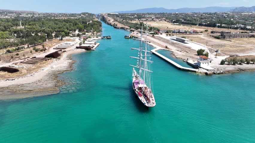 Aerial drone cinematic video of classic sailing boat crossing narrow Corinth canal of Isthmus from West submersible bridge and narrow opening of Corinthian gulf to Saronic gulf, Loutraki, Greece
