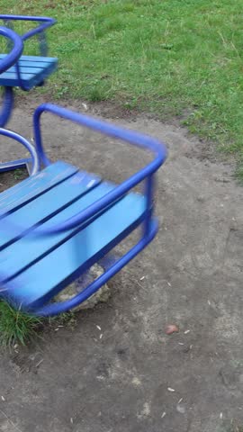 Empty blue carousel on a playground, evoking solitude, childhood memories, and the transience of time, perfect for concepts of nostalgia, play, and abandoned spaces on a gloomy day