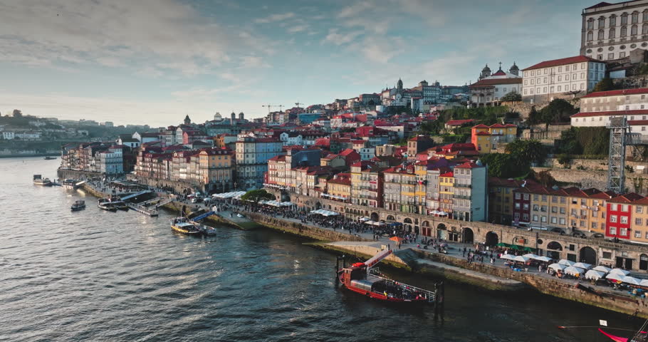 Portugal: Porto city colorful historical Ribeira district buildings slope along the Douro River, and bustling waterfront with boats and many tourists enjoying the cityscape. Aerial view drone panorama