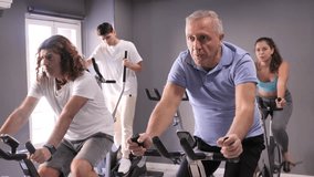 Portrait of elderly man taking indoor cycling class at fitness center, doing cardio riding bike - Powered by Shutterstock - Get 15% off with code: PIKWIZARD15