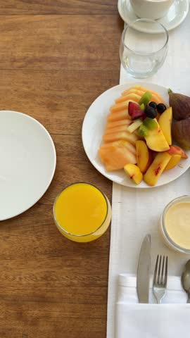  breakfast setting in a restaurant or hotel. There is a glass of orange juice, a plate with an omelette on toast, a salad plate with fresh vegetables, and a plate of appetizers. The interior features 