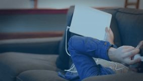 Man reclining on sofa adjusting headphones, raising laptop and initiating rotating tech globe demo. Relaxation, technology, digital, innovation, casual, comfortable, modern - Powered by Shutterstock - Get 15% off with code: PIKWIZARD15